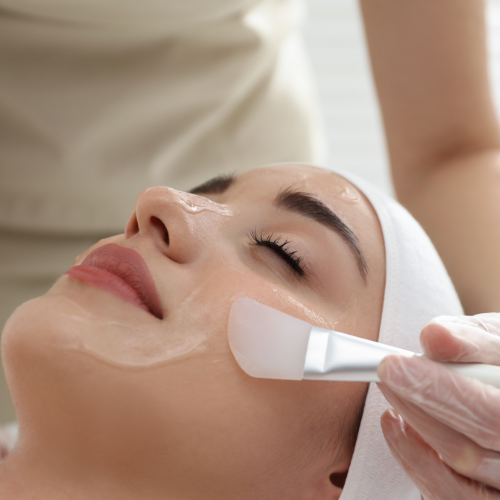 Woman receiving a facial treatment with a gloved hand applying product to her face.