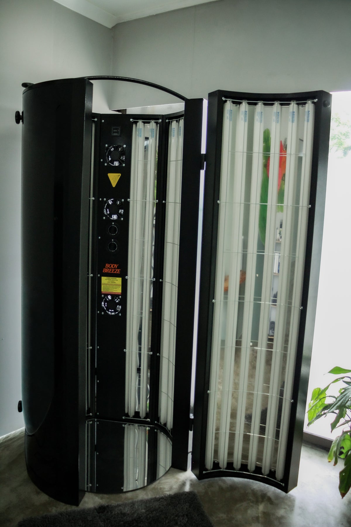 Tanning booth with open door in a room with a plant in Fitneri Wellness in Pretoria