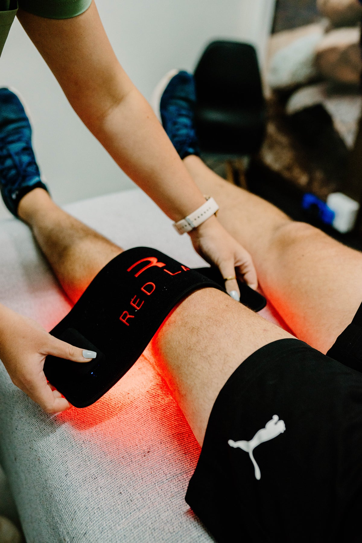 Person receiving red light therapy on a leg with 'Red Light' device on knee injury